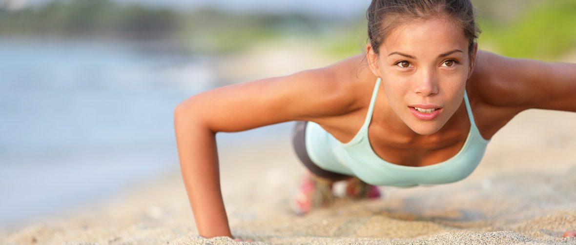 A woman is doing push ups on the beach