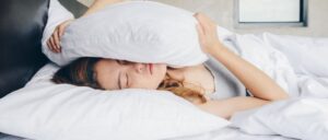 A woman is sleeping under the covers with her head on pillows.